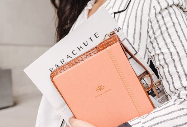 A woman holding undated weekly 2021 Ponderlily Planner in coral