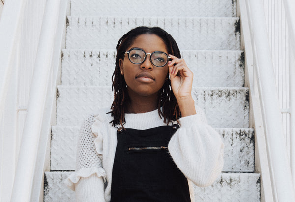 Black woman wearing glasses sitting on stairs