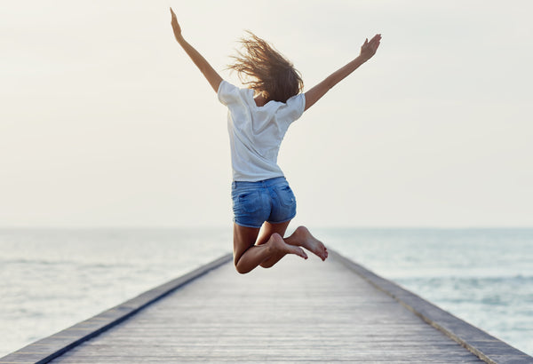 Happy woman jumping along pier
