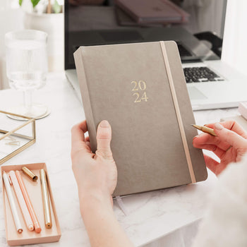 Woman holding 2024 daily Ponderlily planner on desk