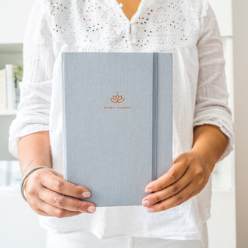 Woman holding the Warm Gray Ponderlily weekly planner